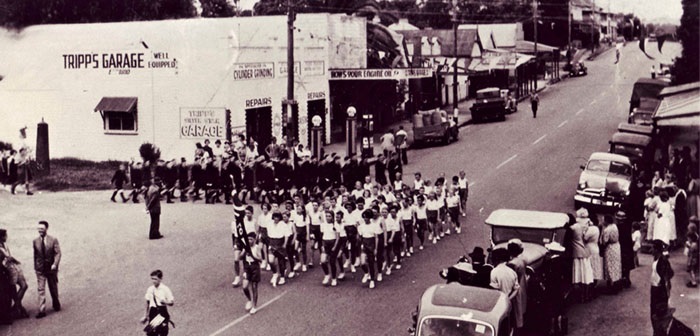 Schoolchildren from Minto Public School marching in procession, passing Tripp's garage c.1950. Follan Coll