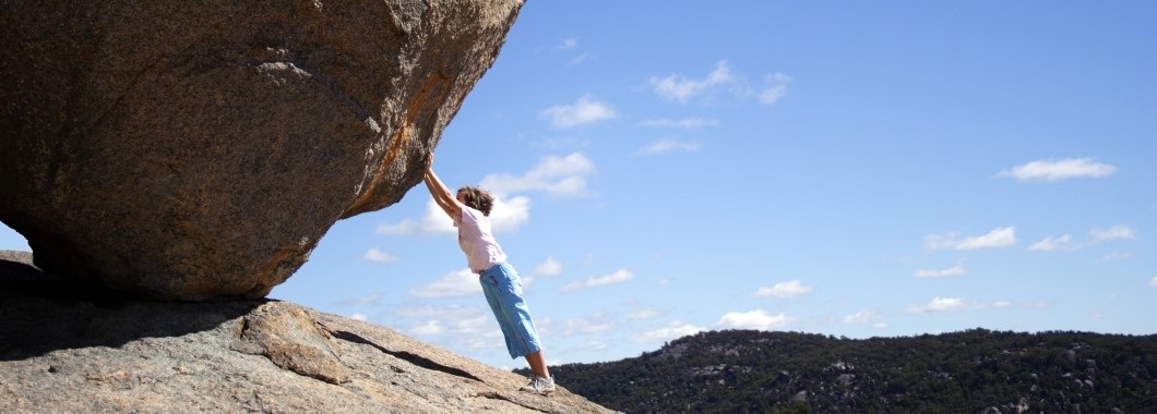 Illusion of child holding up large boulder