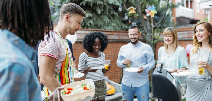 Six adults gathering around a barbeque