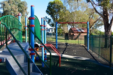 The playground has both fencing and soft-rubber fall covering