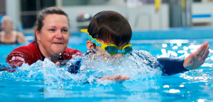 A swimming instructor teaching a kid how to swim