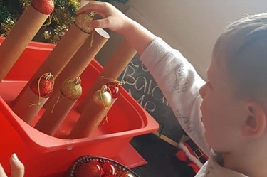 Child playing with Christmas baubles