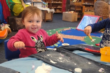 Girl in a pink jumper painting