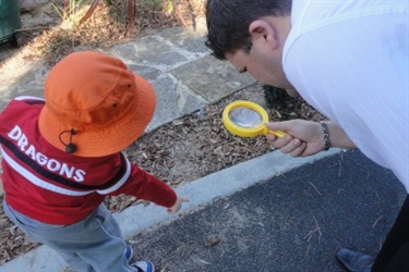 Educator and child using magnifying glass