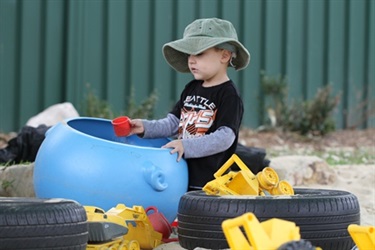 Boy in sand pit with tyres