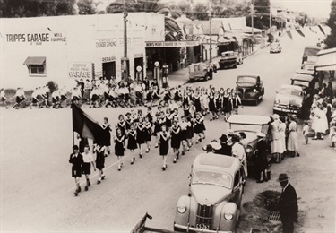 Boy scouts pass Tripps Garage in a parade along Queen Street, Campbelltown passing the corner of Dumaresq Street, celebrating the coronation of Queen Elizabeth II in 1955. Jack Hepher collection.