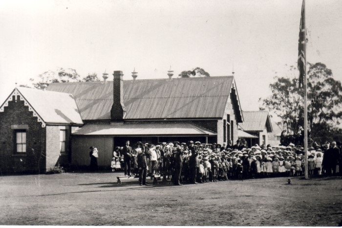 Black and white photograph of school students outside a federation style school house