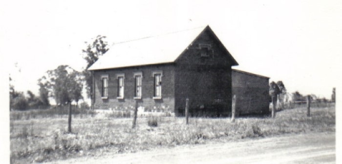A black and white photograph of St Peter's old school house building in a rural setting 