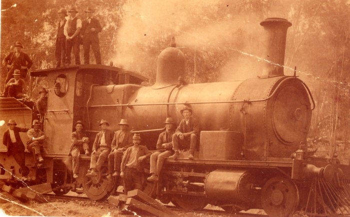 An old sepia photograph of a steam train and the work men around it 