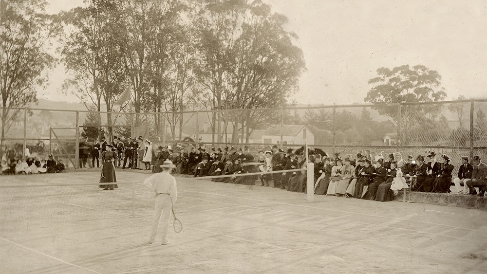 an old photograph of an early 1900s tennis match, with spectators