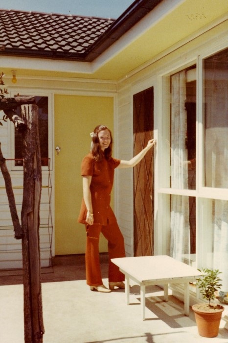 A young woman in 1960s fashion on her front porch