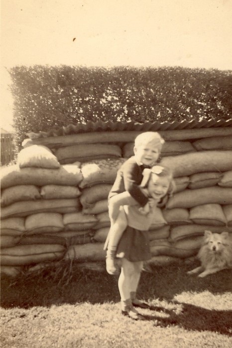 children playing with an Air Raid shelter in the background 