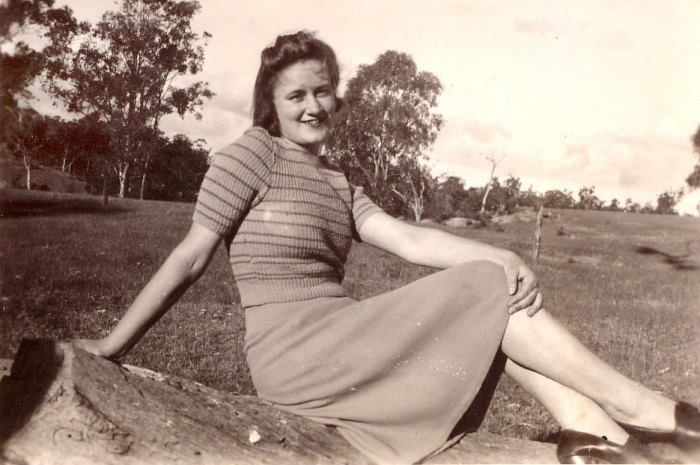 A young lady posing for a photograph with a rural landscape behind