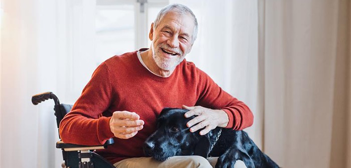 An elderly man sitting in a wheelchair with his dog
