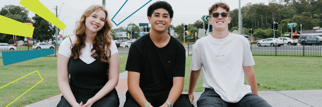 A group of three youths sitting down outside