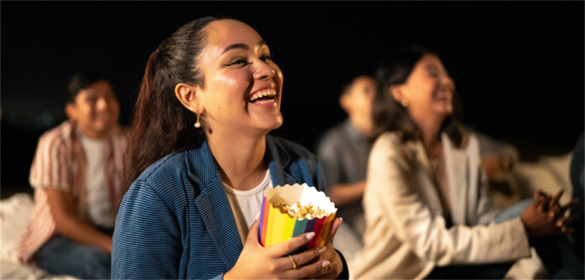 Young people sitting with popcorn at night cinema