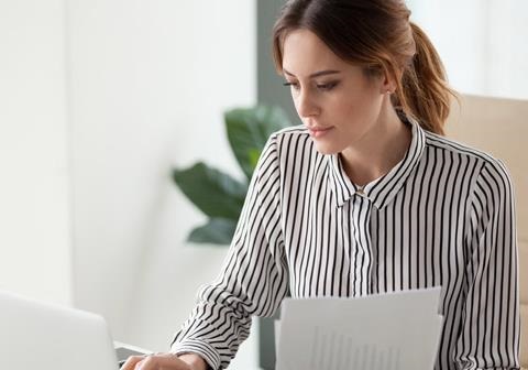 Woman wearing a black and white pinstripe shirt seated using a laptop