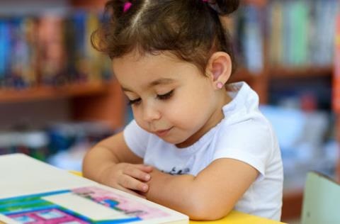 Small child reading at table