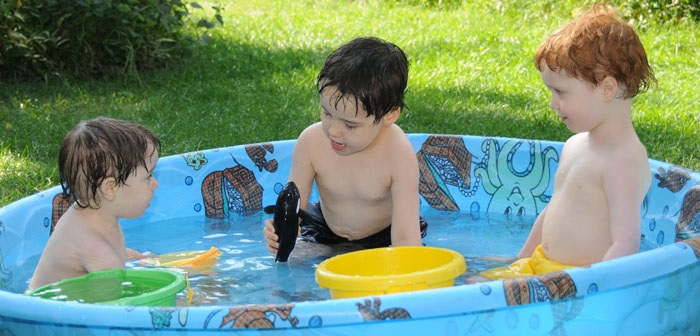 Portable swimming pool in backyard with three young boys